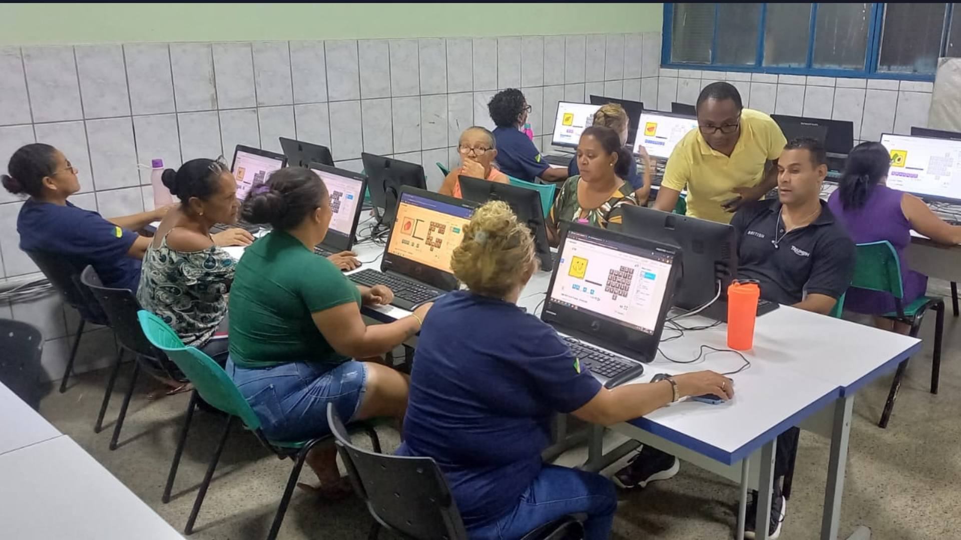 Adultos e idosos mexendo no computador com a ajuda do professor