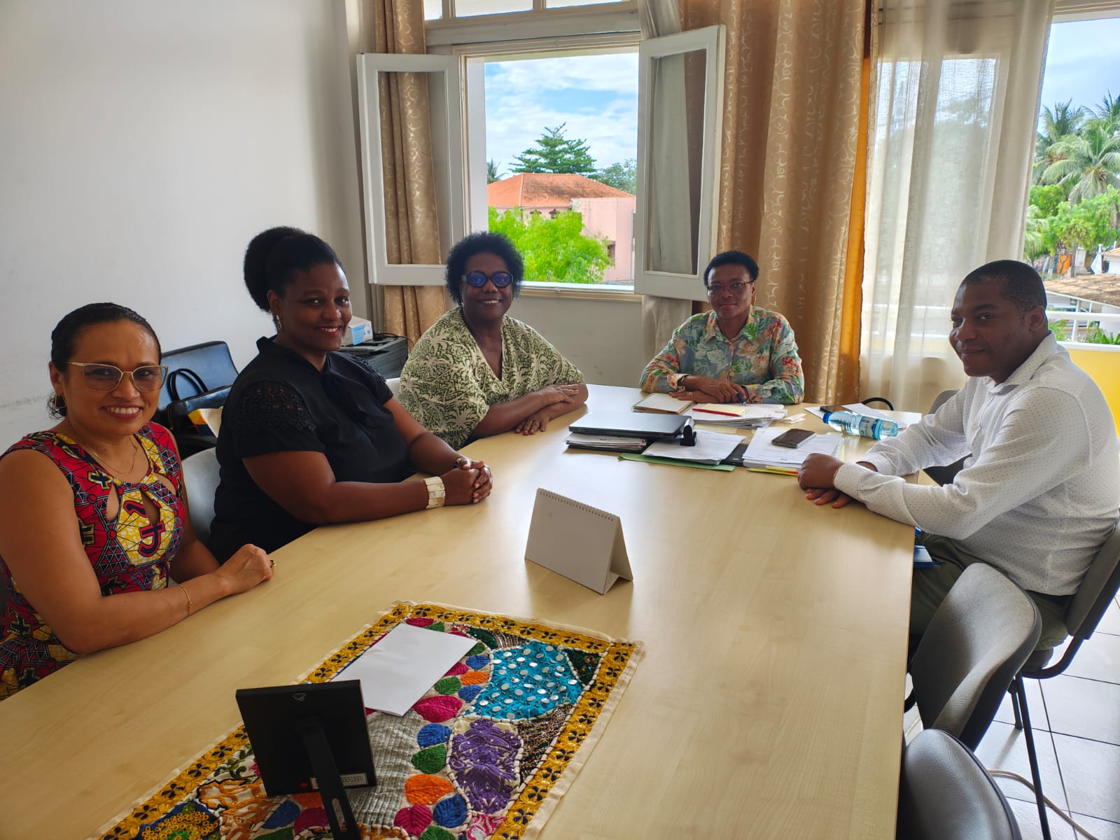 Pessoas posando para foto sentadas ao redor de mesa.